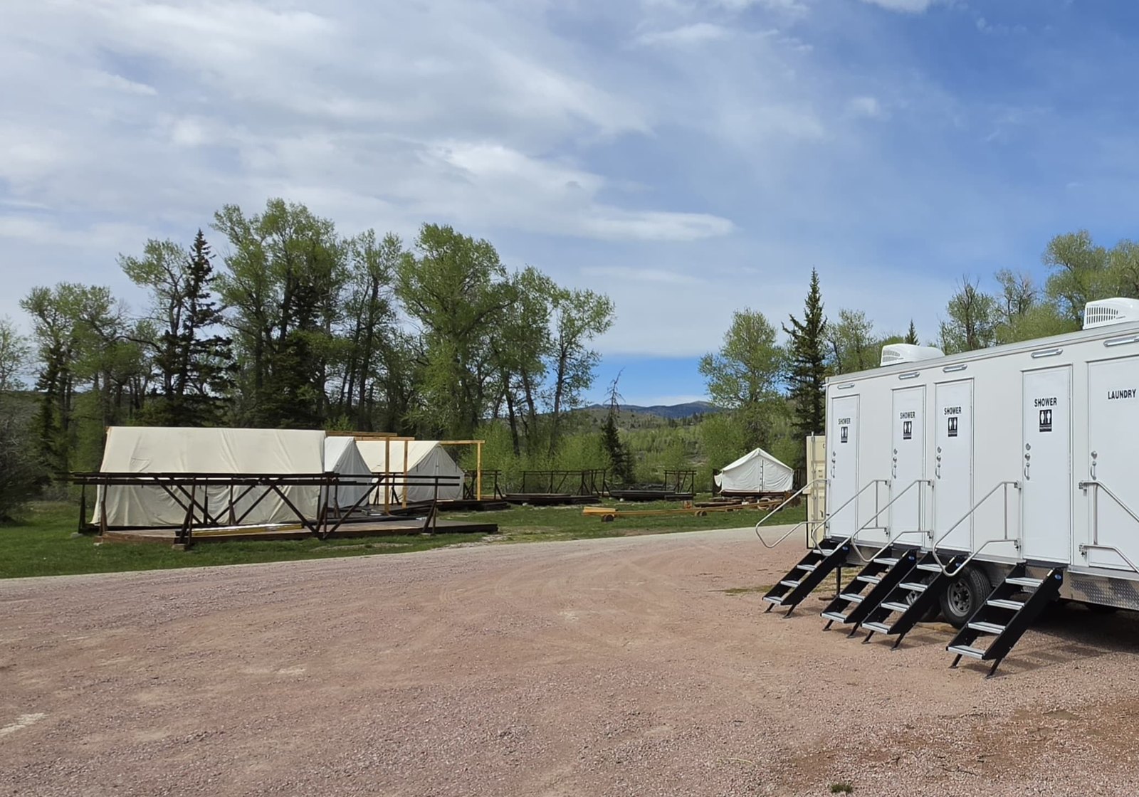 Shower trailer at a mountain base camp in the Colorado high country with peaks and pine forest behind it